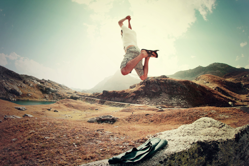 man jumping on landscape near mountains