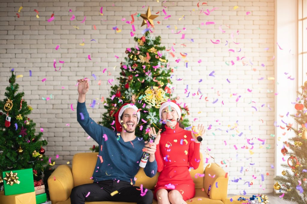 man-and-woman-wearing-santa-hats-sitting-on-sofa-popping-a-3183392