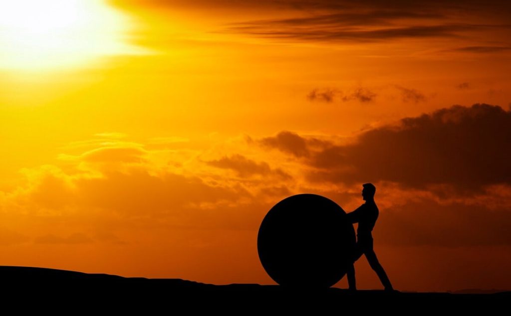 challenge-difficult-man rolling huge ball up hill