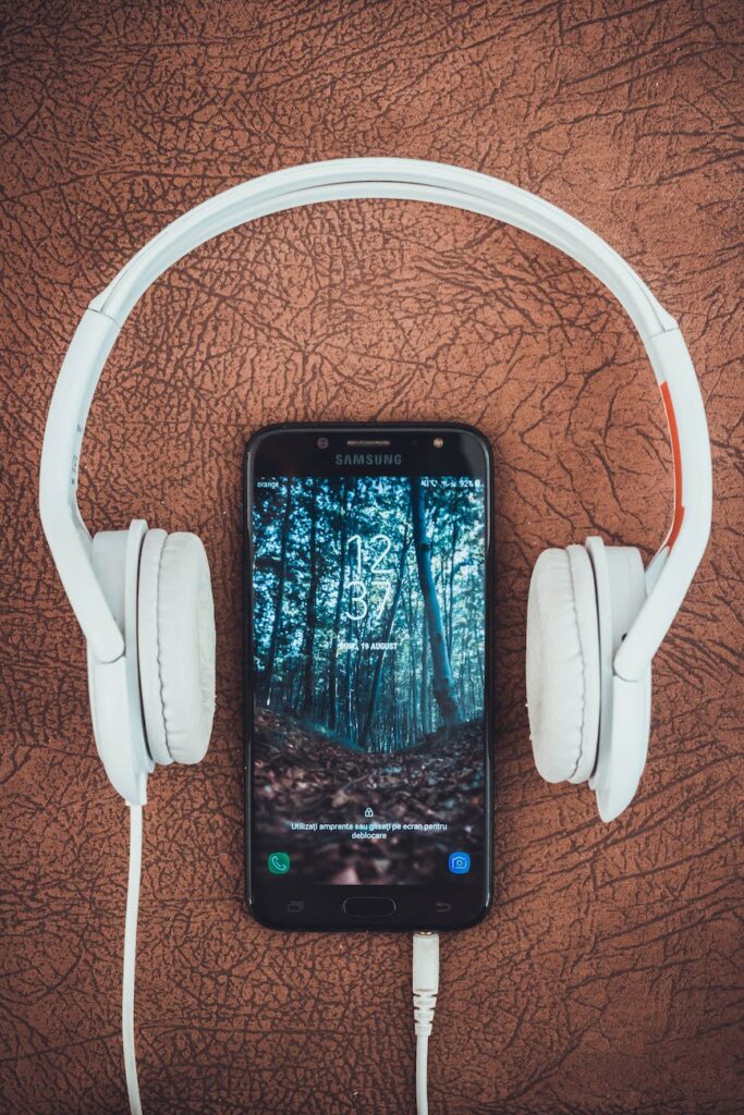 turned on black samsung smartphone between headphones