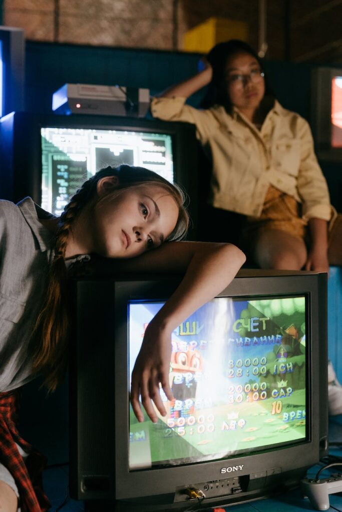 two girls leaning on televisions