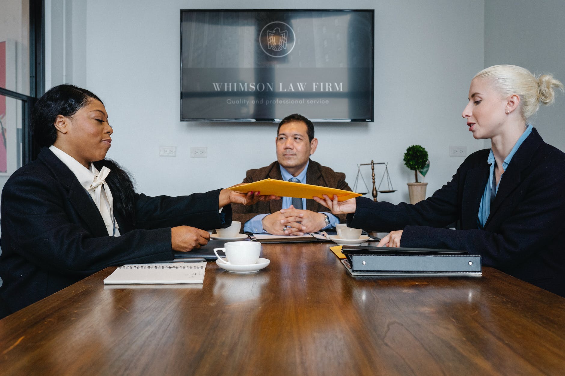 black judge giving yellow envelope to young businesswoman