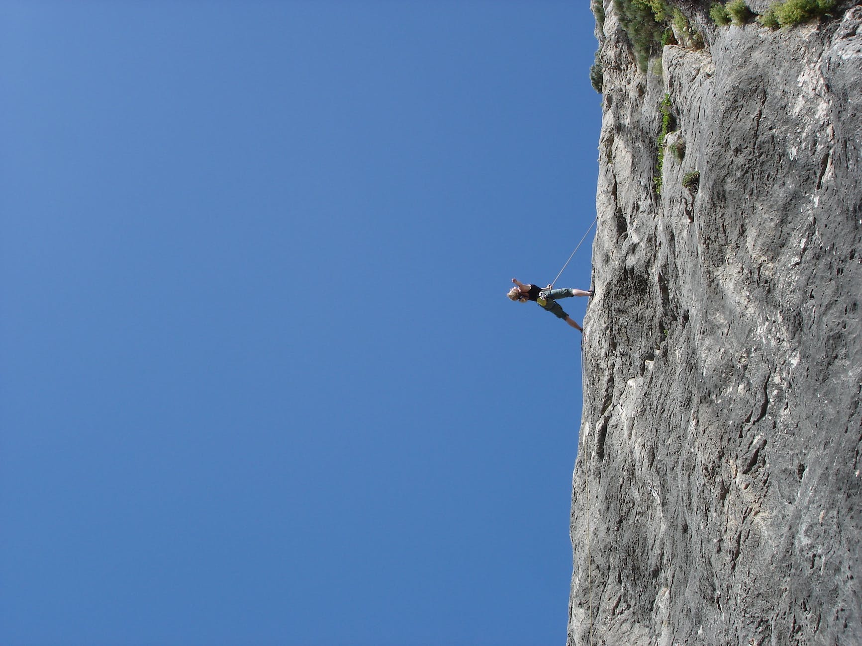 man standing on rock against clear blue sky