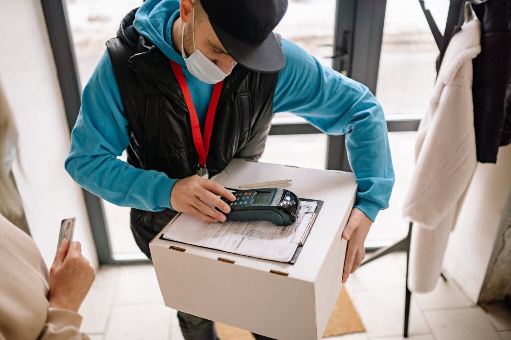 man in blue hoodie and black dawn vest holding box