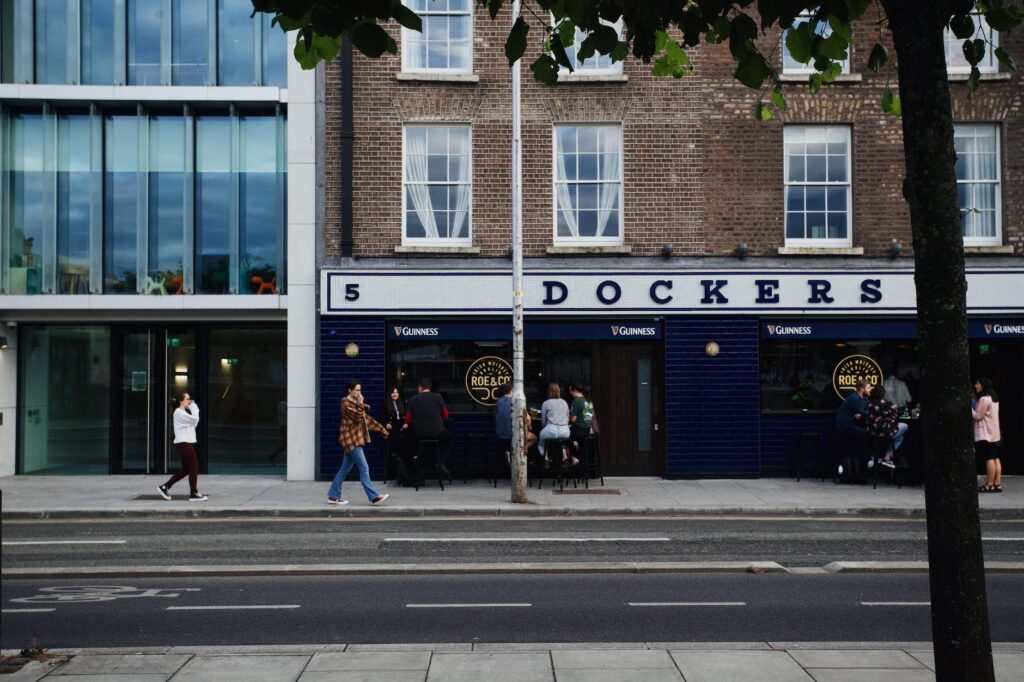 people walking on sidewalk in front of a cocktail bar