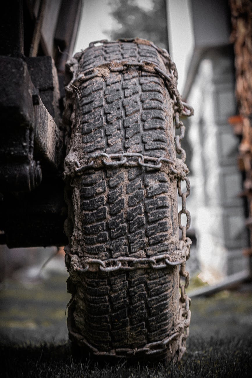 close up photo of muddy tire wrapped in rusty chains