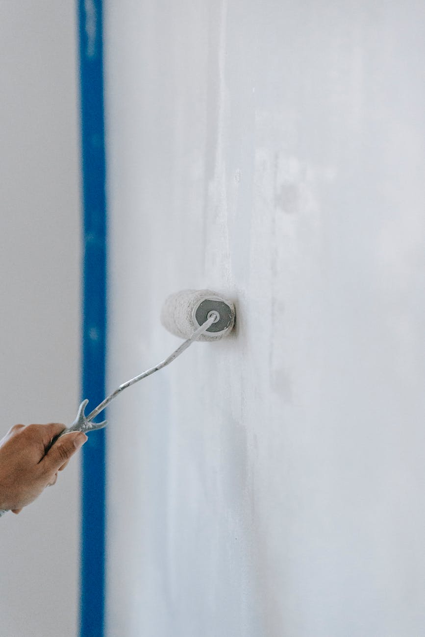 person painting the wall with a roller
