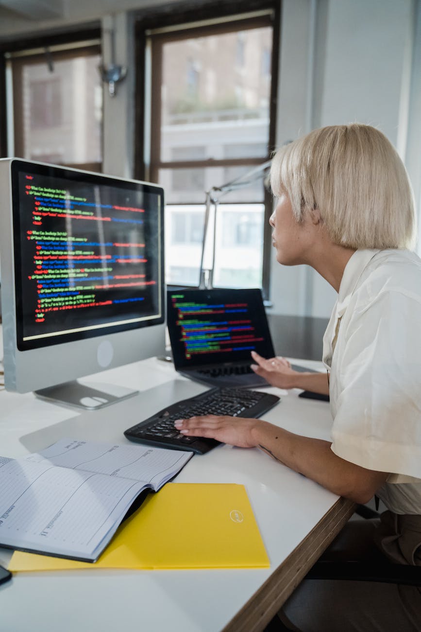 vertical shot of a blonde woman looking at screen with multicoloured code