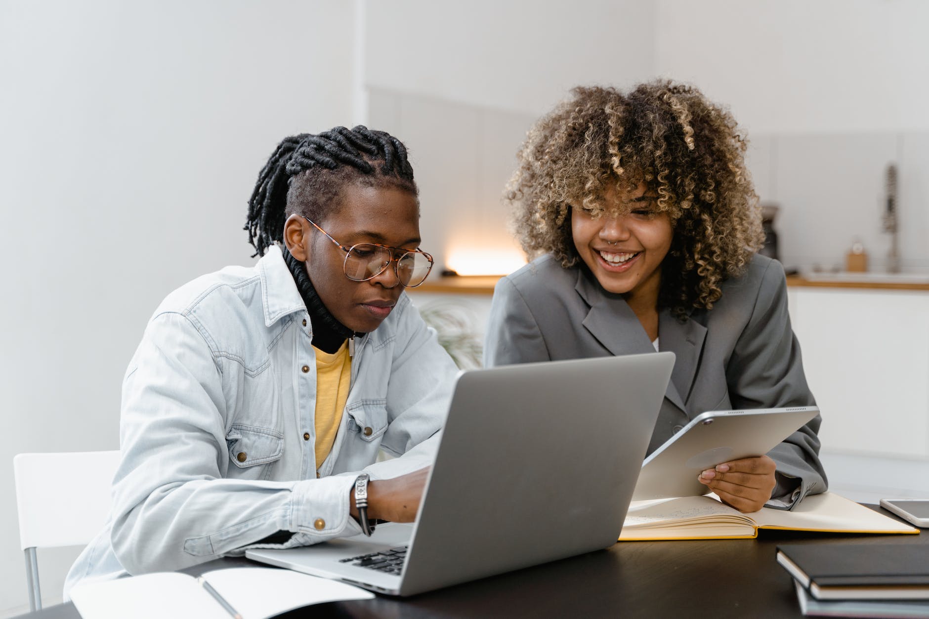 a man and woman having conversation while sitting near the table with laptop