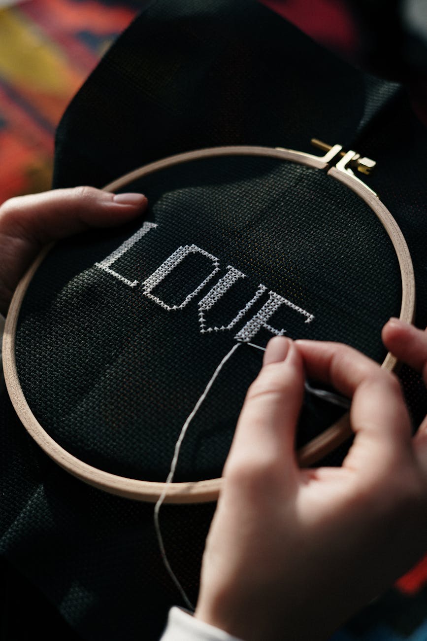 person hand embroidering on black textile