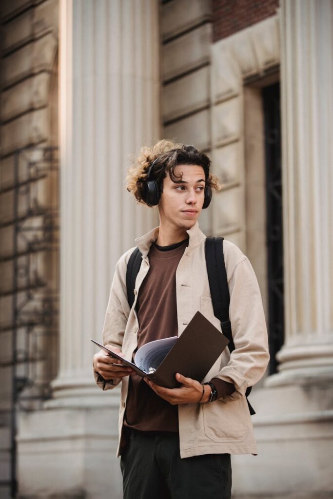 ethnic male standing near building with folder