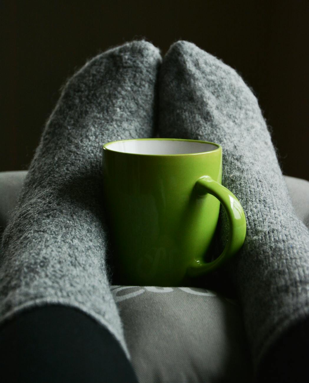 green ceramic mug on person s feet