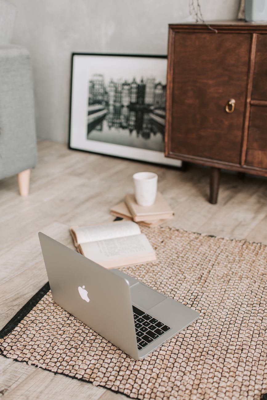 laptop and books on floor carpet