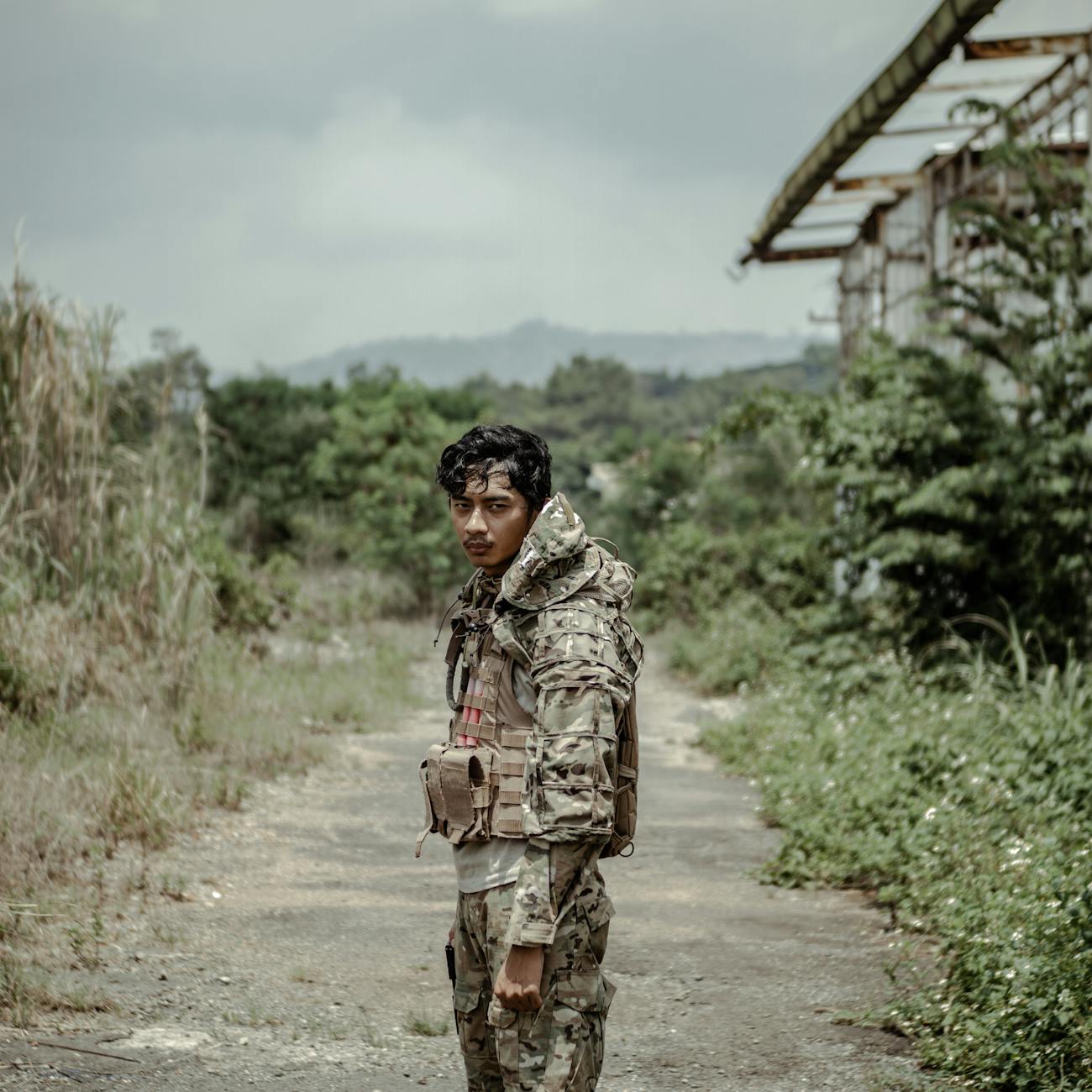 wistful ethnic soldier standing on footpath in countryside