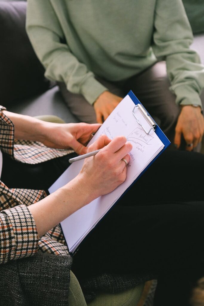 woman psychologist taking notes on clipboard while talking with client
