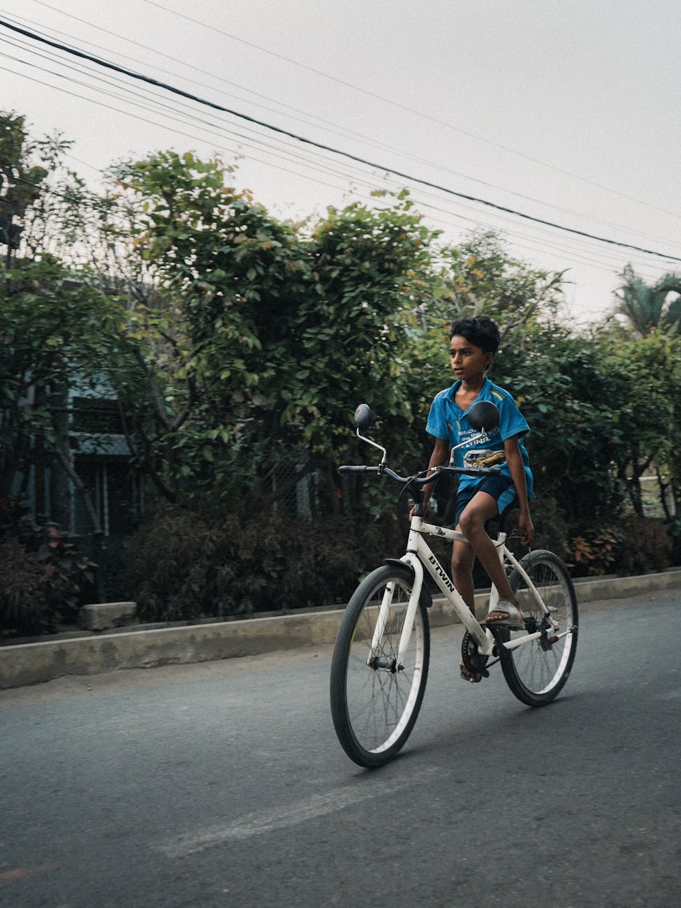 boy riding bicycle on street in village