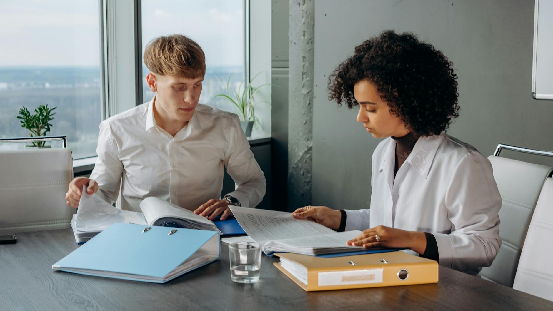 colleagues in white long sleeve shirts sitting and reading a financial report on a conference room