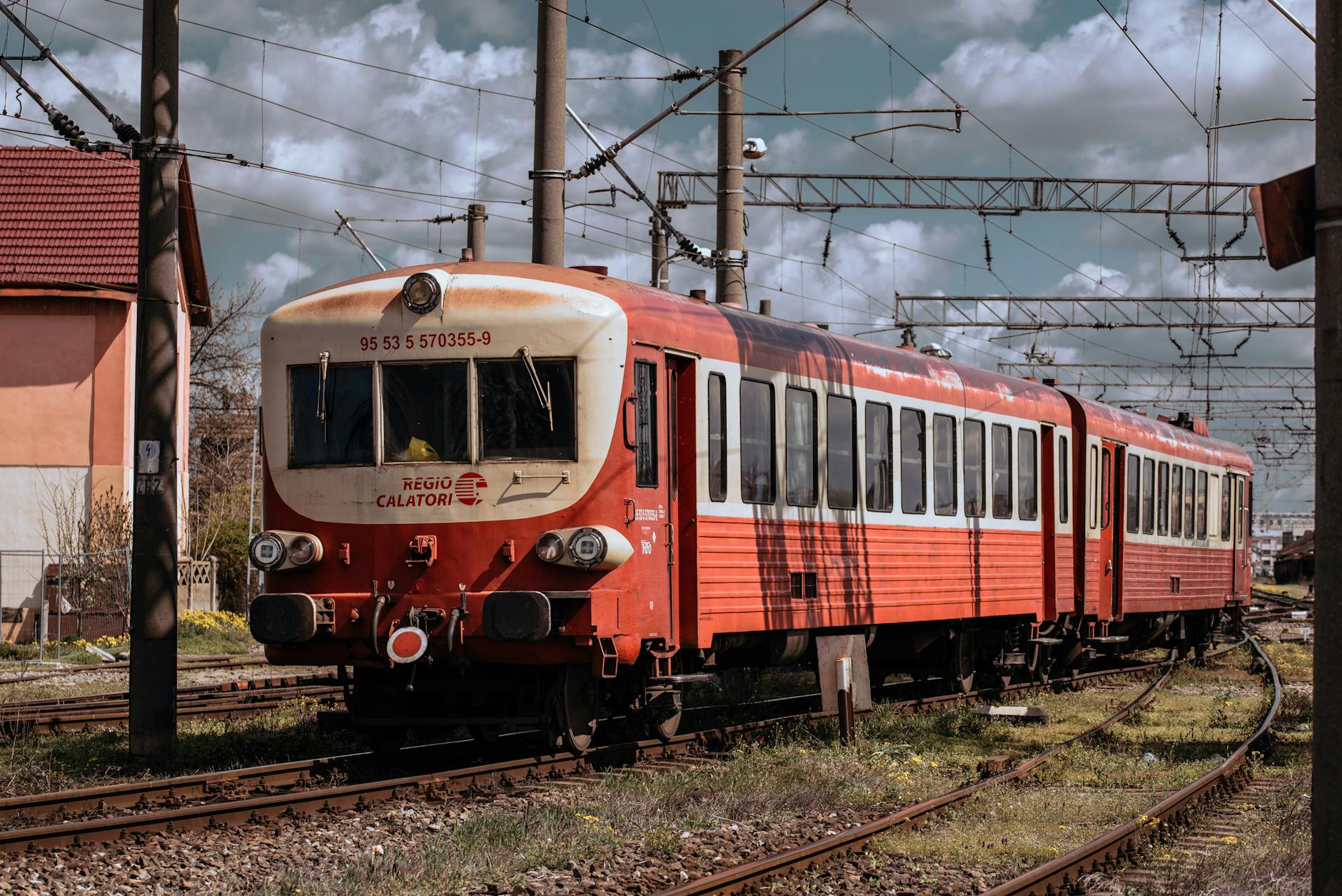 a red train on the tracks next to a power pole