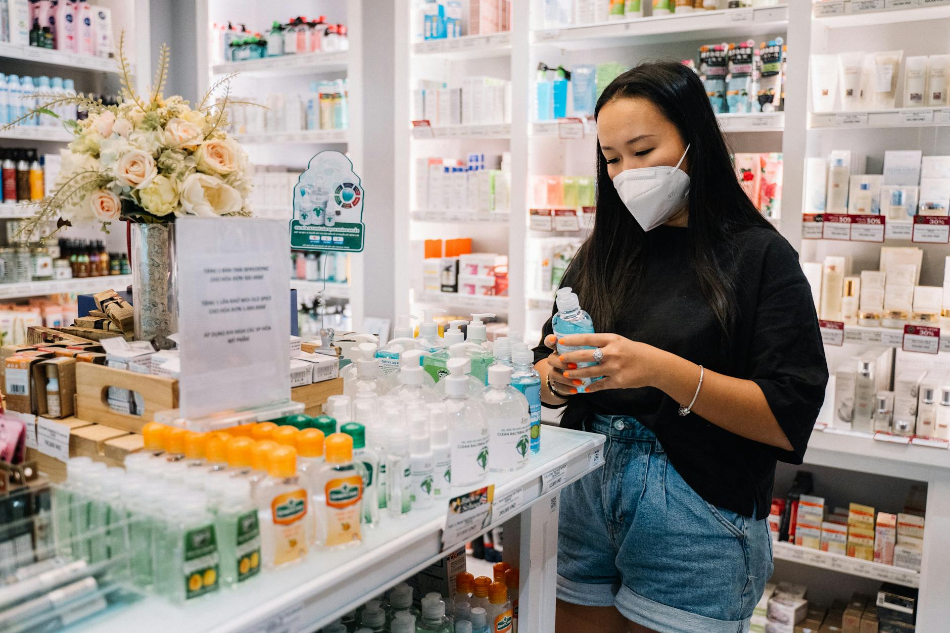 woman with face mask holding an alcohol bottle