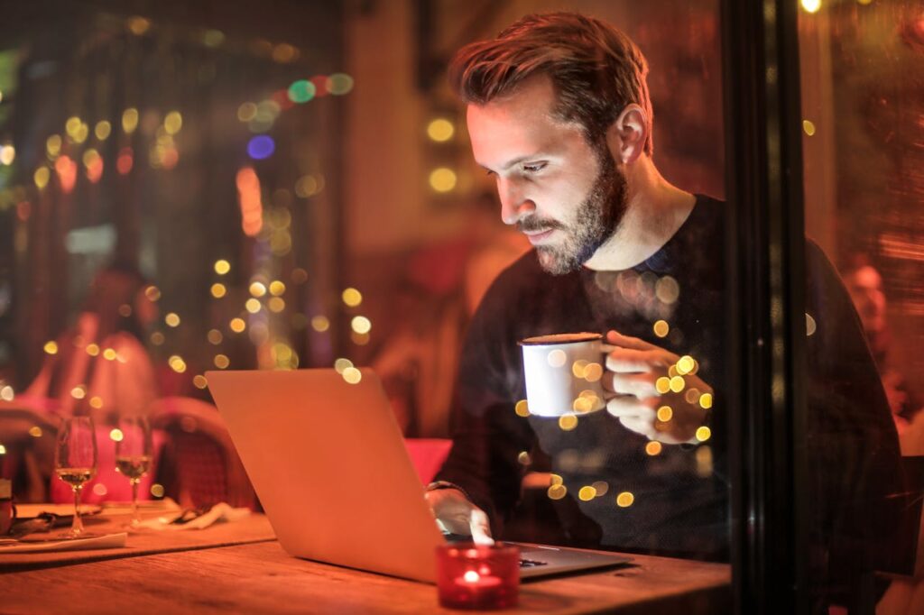 Man holding a mug in front of laptop