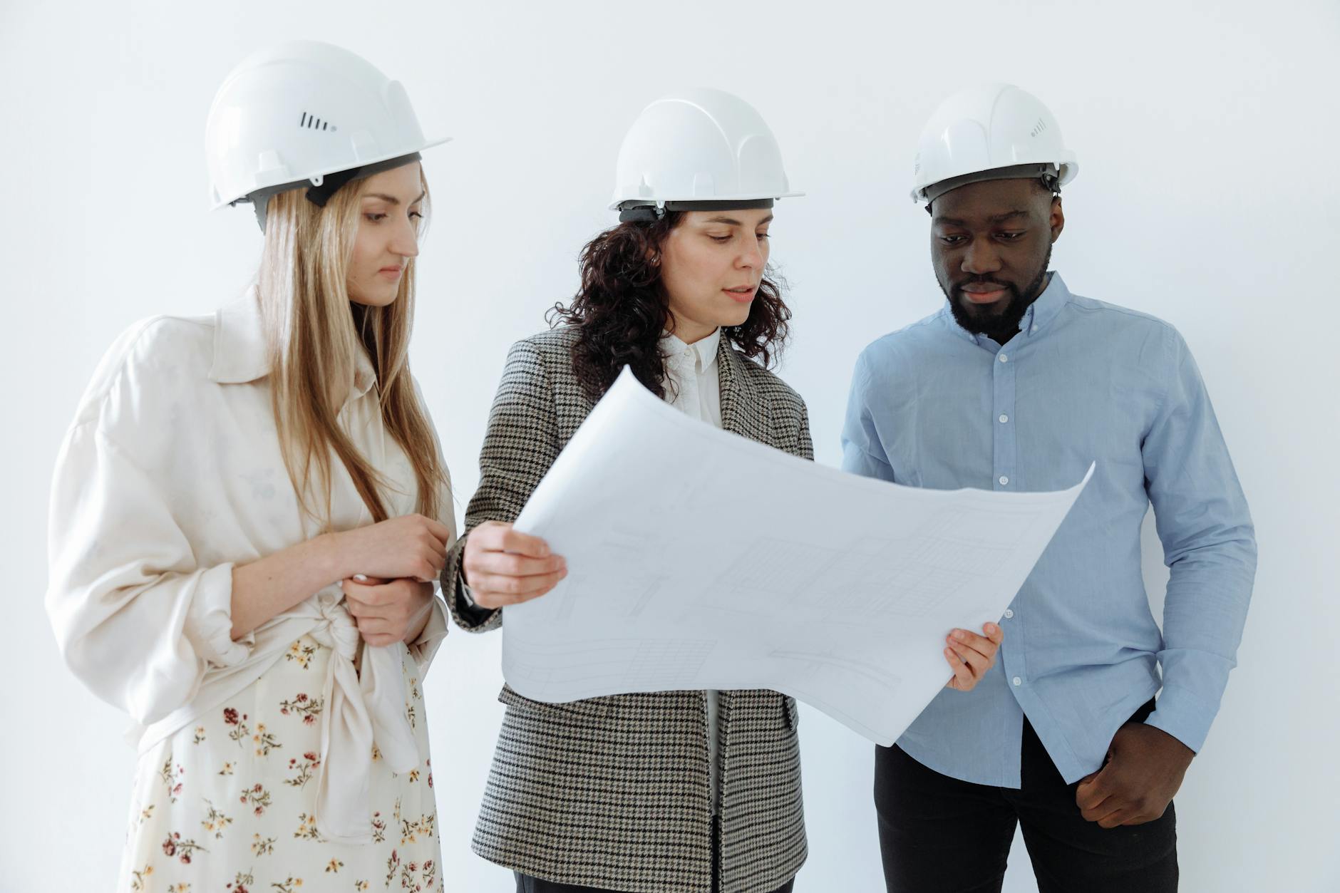 people in hard hats looking at the big sheet of paper