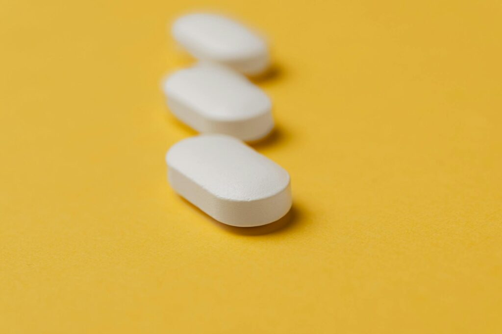 set of white pills on yellow background