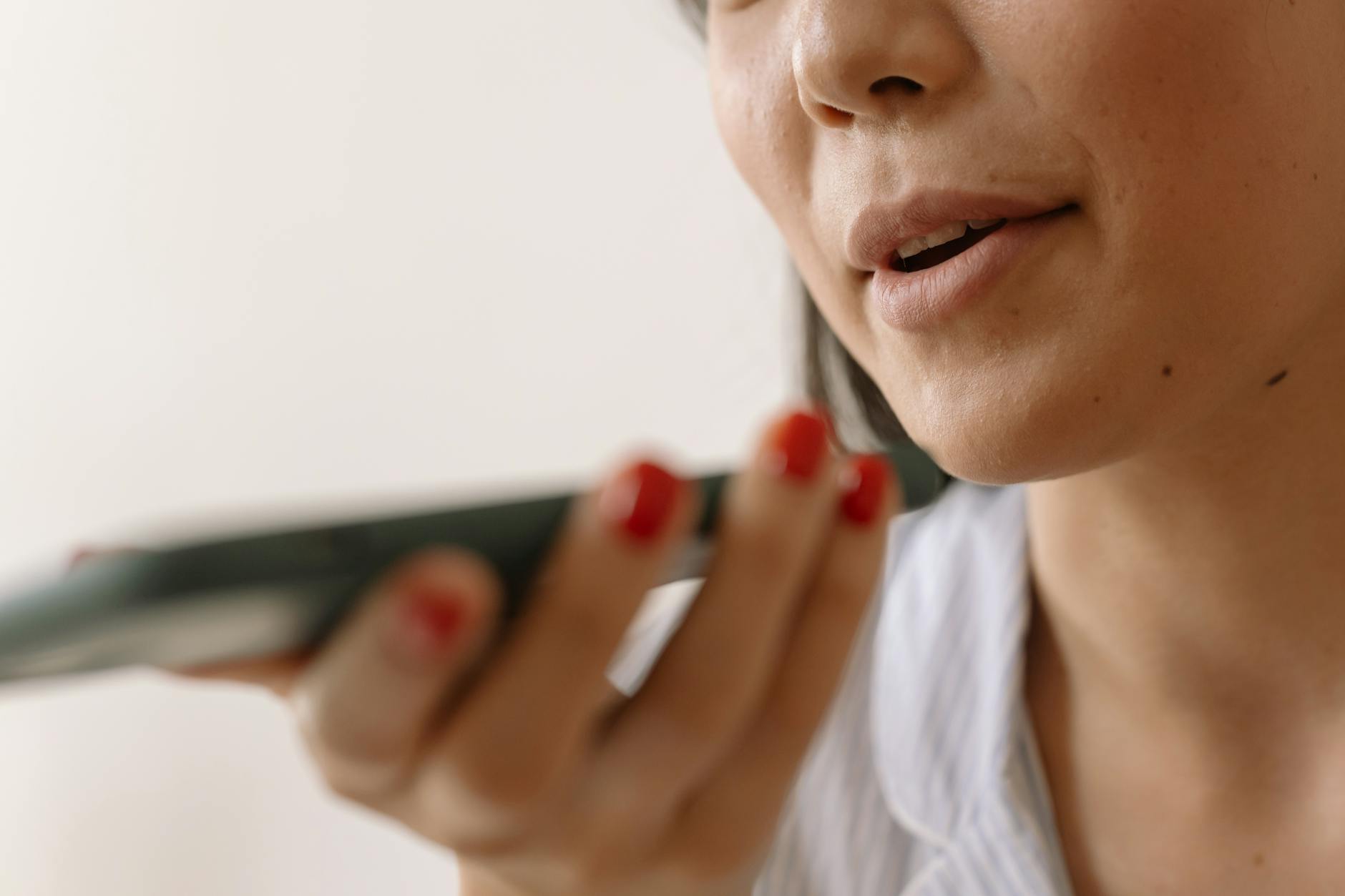 close up of a woman speaking to the mobile phone microphone