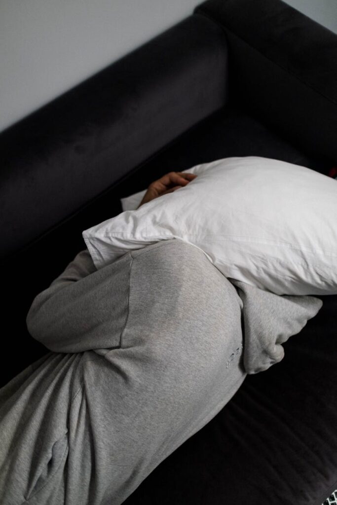 a man covering his head with a pillow while lying on the bed