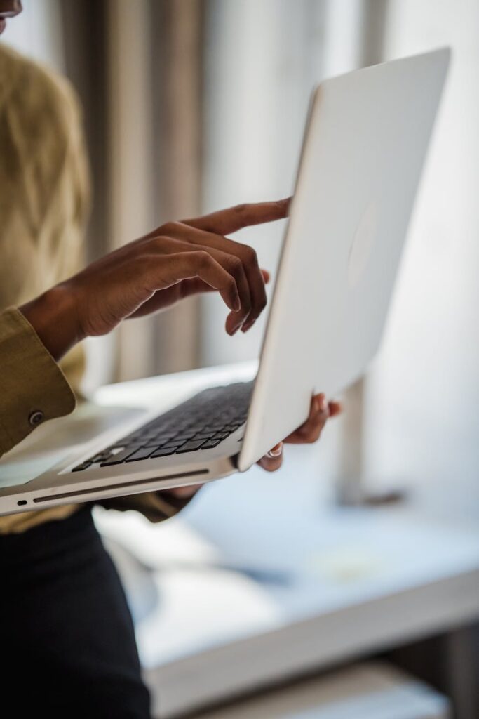 close up of womans hands holding laptop and pointing at the screen