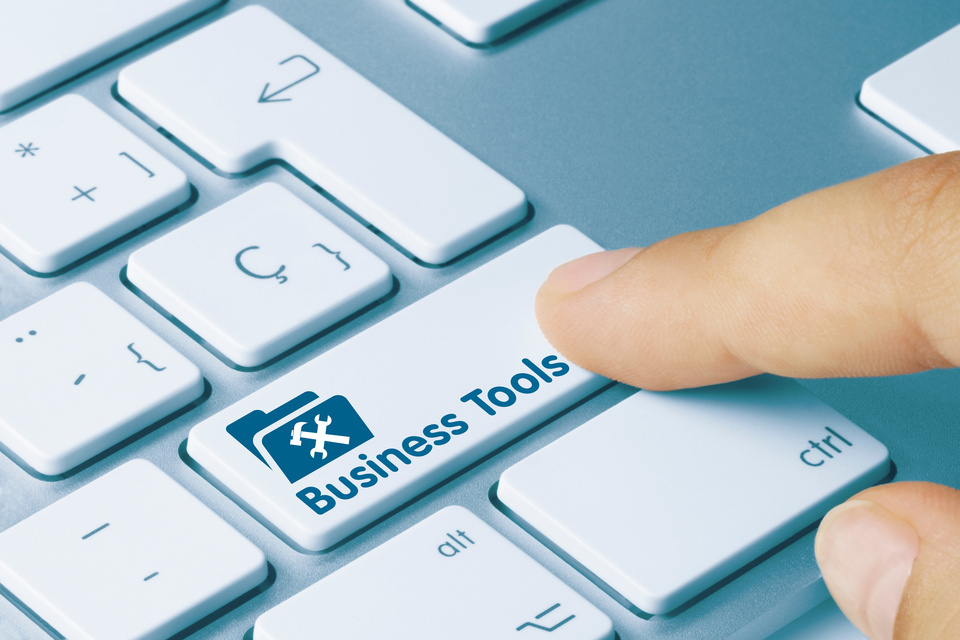 A close-up of a finger about to press a button on a white computer keyboard that reads "Business Tools."
