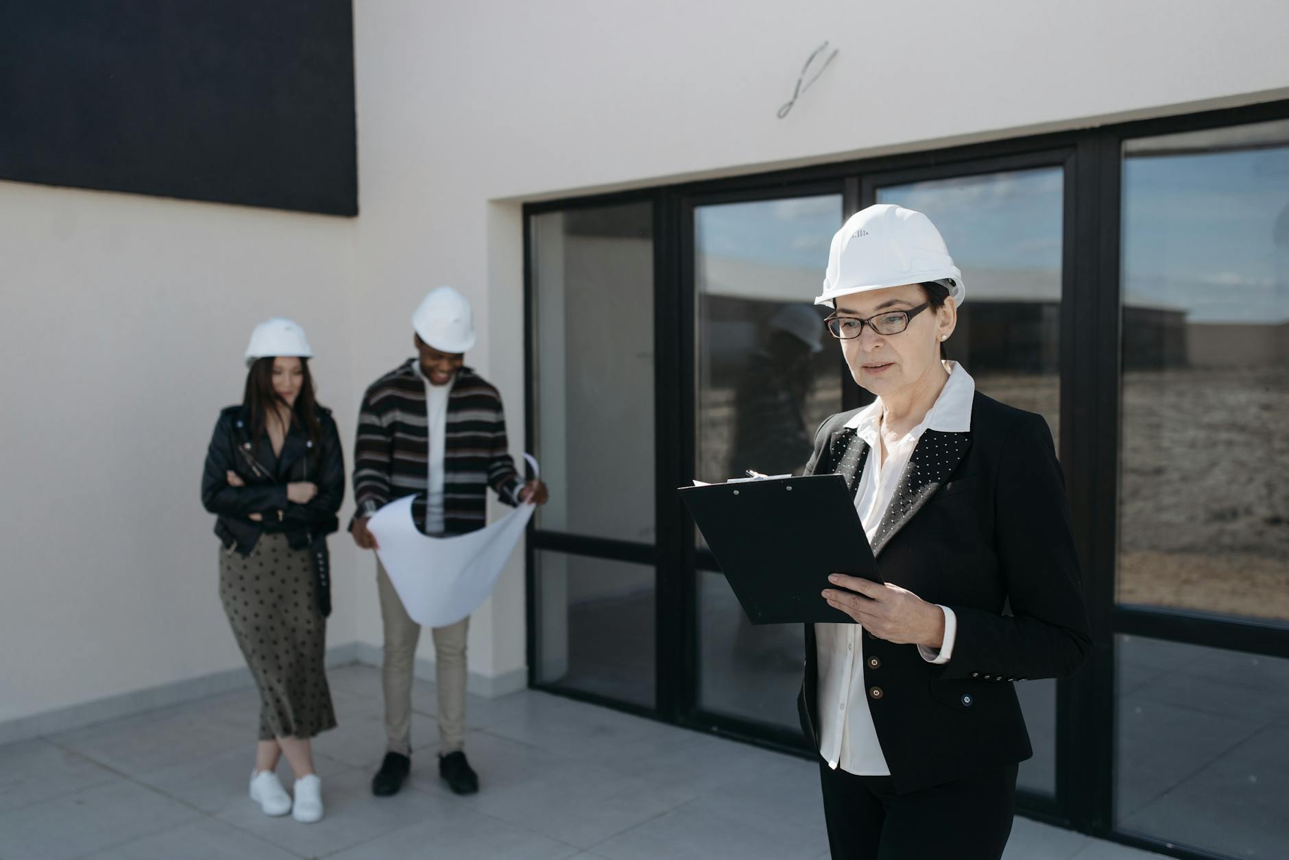 seller in suit and clients standing by house windows