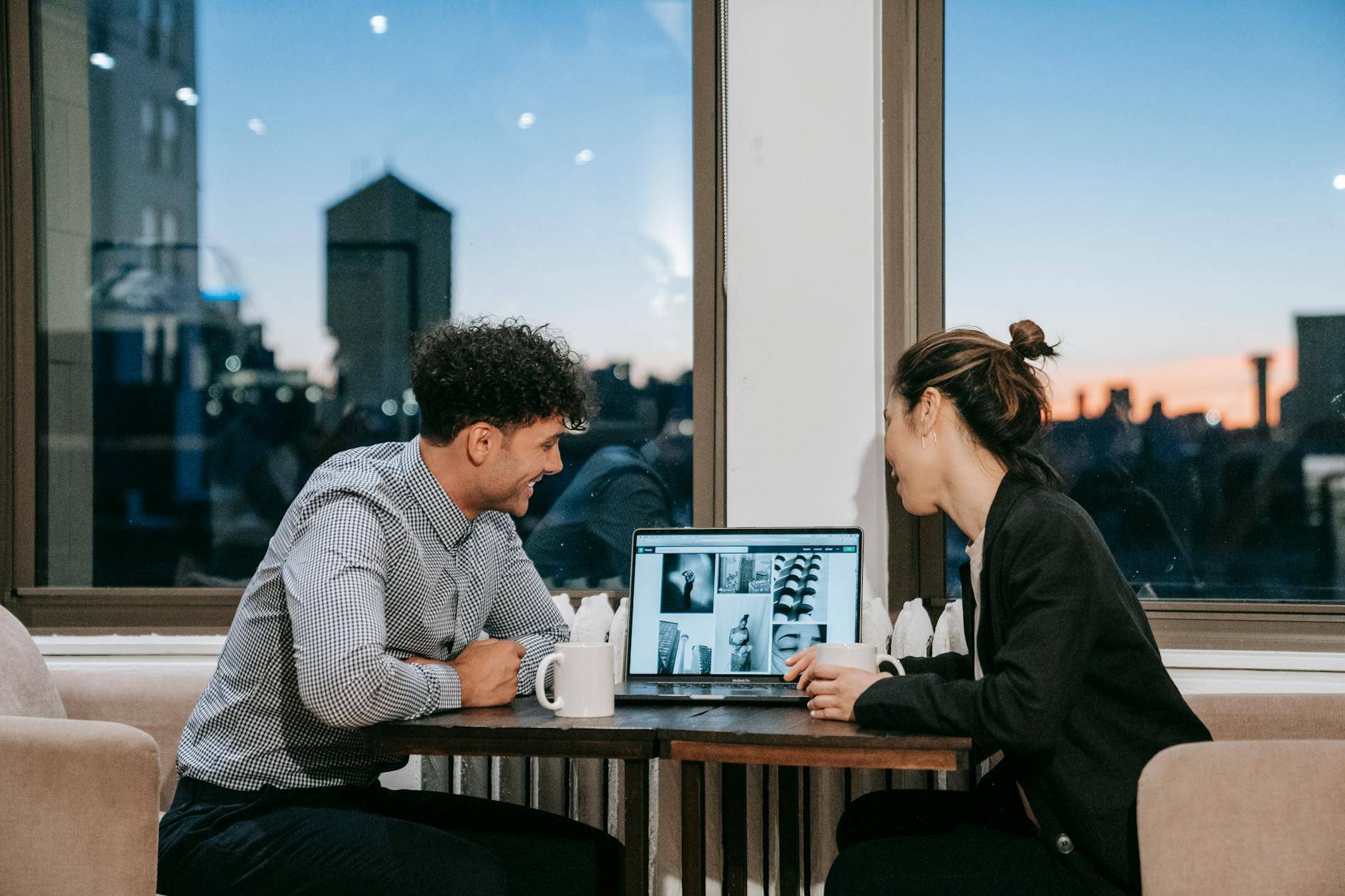 a man and a woman looking at a laptop on a table
