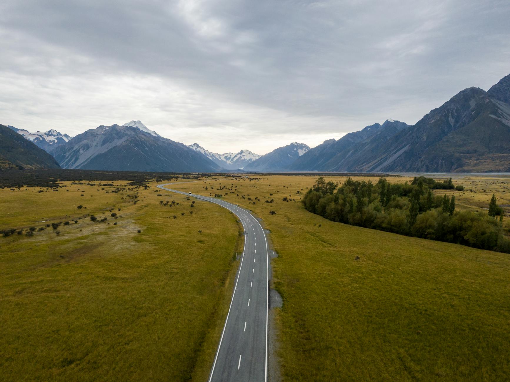 aerial photography of country road between green grass field
