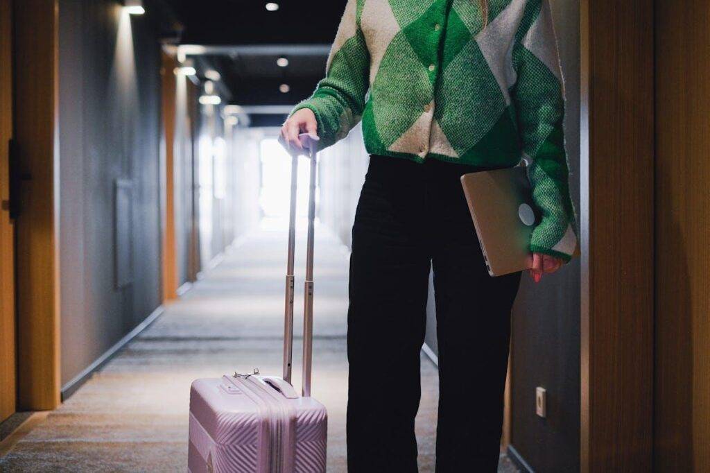 A person holding a laptop and holding luggage