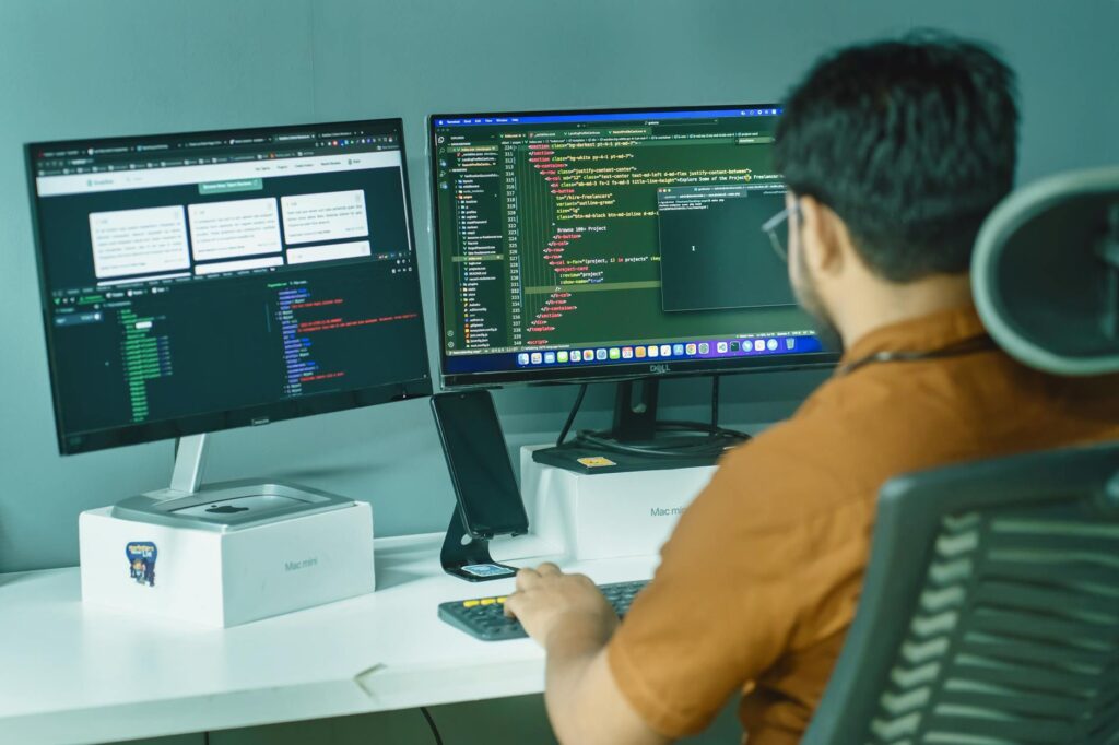 a man sitting at a desk with two monitors