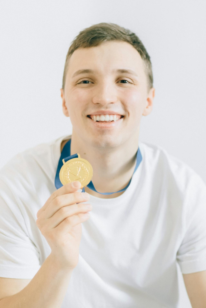 Smiling Boy in White Crew Neck Shirt Holding a Medal