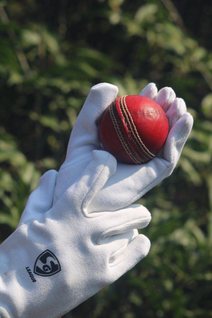 cricket ball held in gloves outdoors