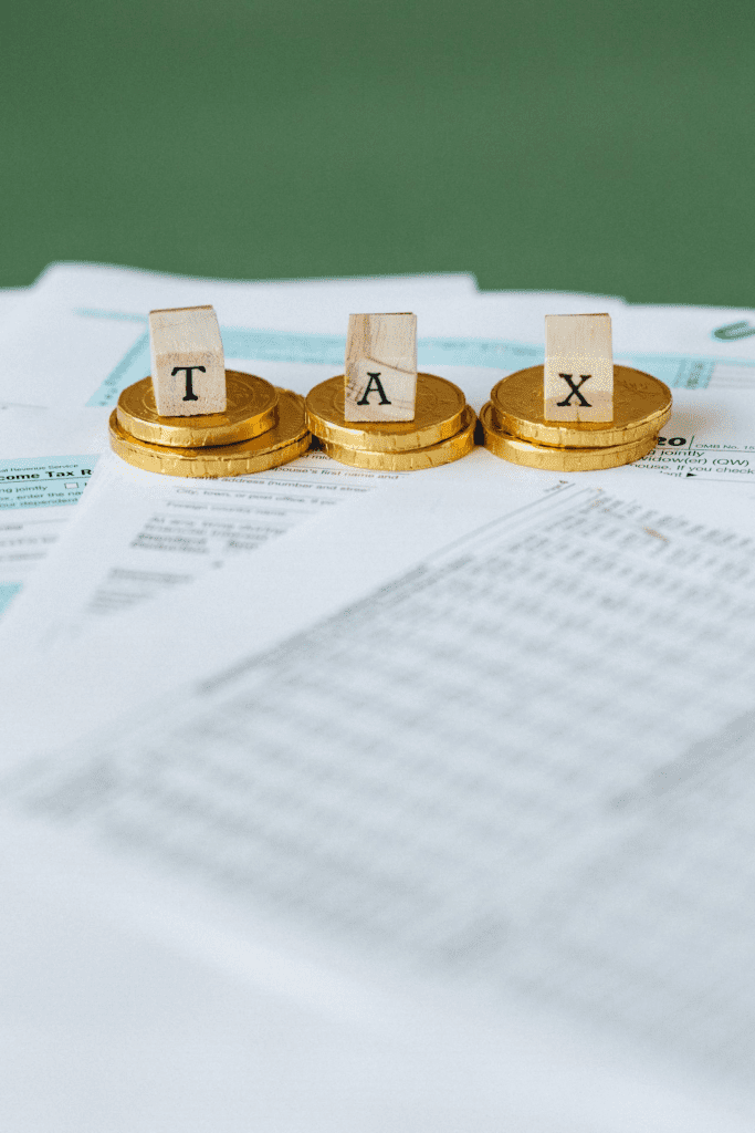 Tax documents with gold coins and wooden blocks spelling TAX, conveying tax or financial theme.