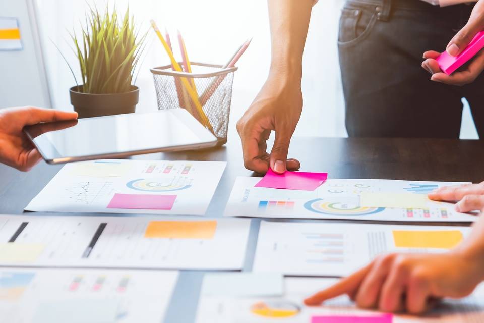 Team brainstorming in a startup meeting, collaborating over notes and ideas with documents on top of a table.