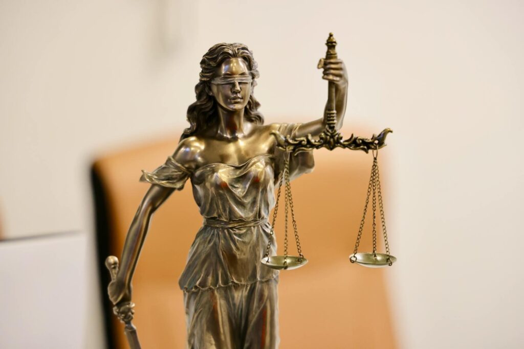 Bronze statue of Lady Justice wearing a blindfold, holding scales in one hand and a sword in the other, symbolizing justice and the law.