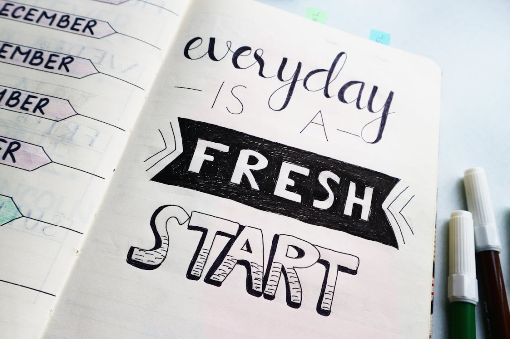 Notebook page with hand-lettered quote 'everyday is a fresh start' and colored markers along the edge.