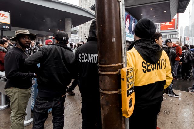 Diverse crowd at a city event with security personnel managing the gathering