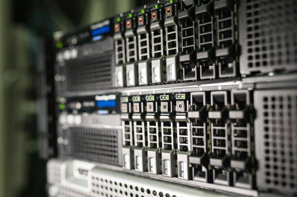 Server rack with numerous hot-swappable drive bays and blinking green LEDs in a data center.