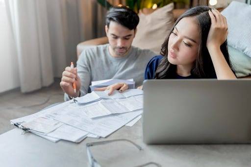 image - Lead Grow Develop - Business, Technology, Personal Development A couple sits on the floor surrounded by scattered bills, with a laptop nearby, looking stressed as they discuss finances.
