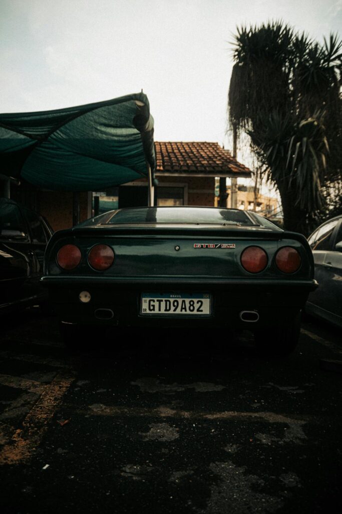 Rear view of a classic vintage car parked outdoors under a canopy, showcasing its iconic design and color