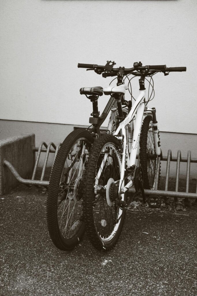 Two mountain bikes parked in urban bike rack, grayscale photo