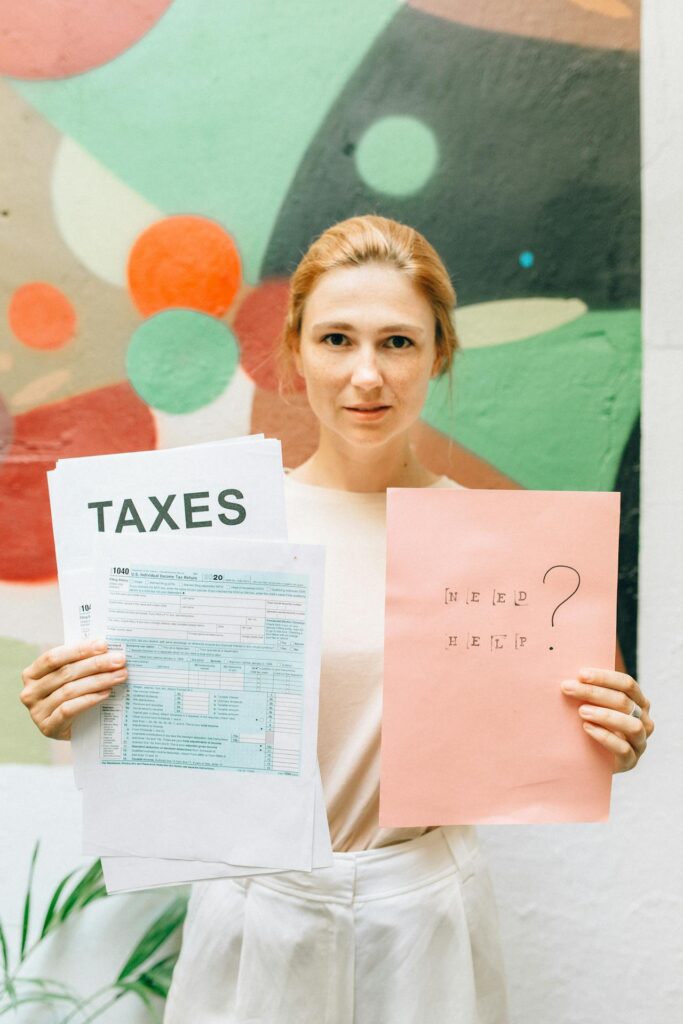 A professional woman holding tax documents and a 'Need Help?' sign, offering tax assistance