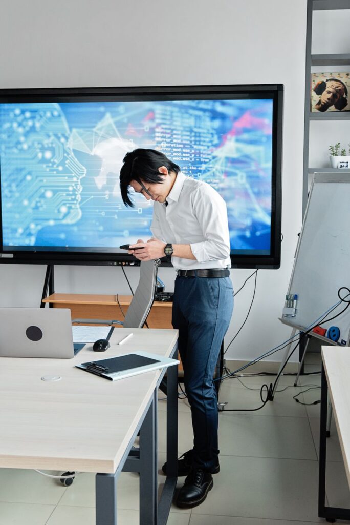 pexels-photo-7988792 - Lead Grow Develop - Business, Technology, Personal Development man in white long sleeve shirt and blue pants standing while holding black mobile phone