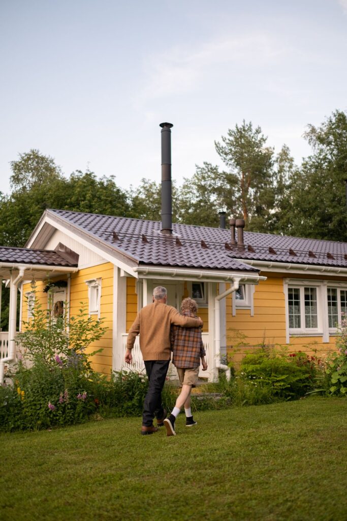 pexels-ron-lach-10397938 - Lead Grow Develop - Business, Technology, Personal Development A serene moment of togetherness as a grandparent and child walk by a charming yellow cottage in lush greenery
