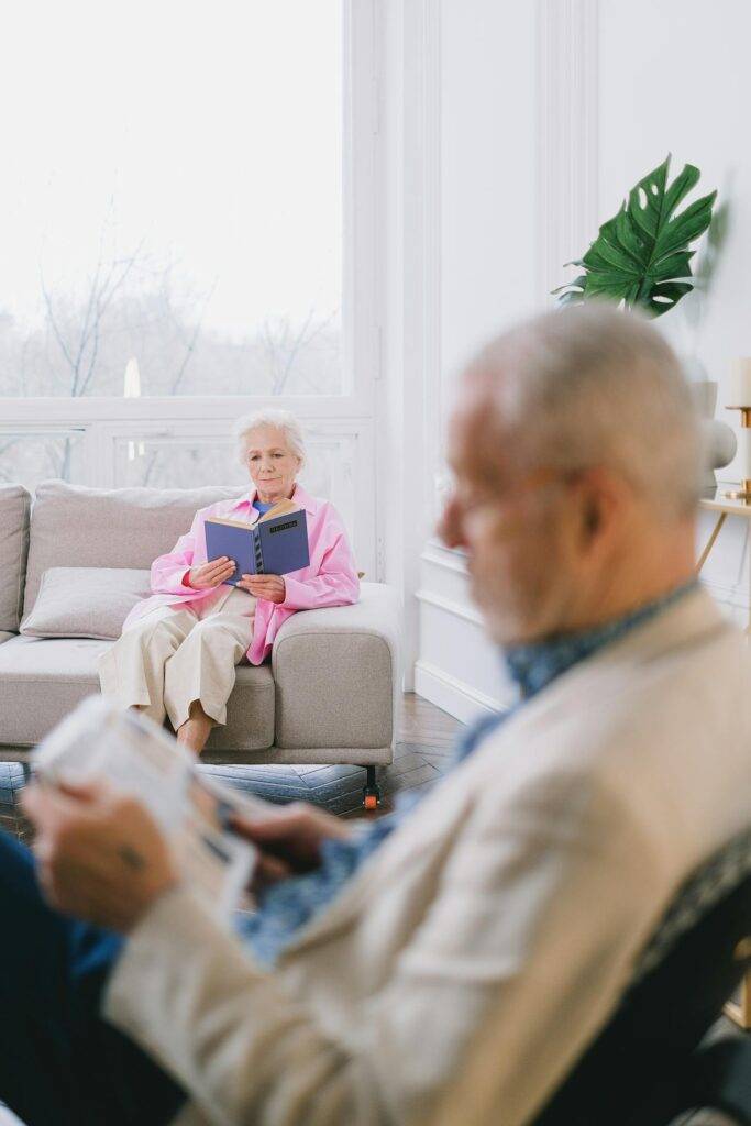 A senior couple enjoys reading in a cozy, well-lit living room with modern decor.